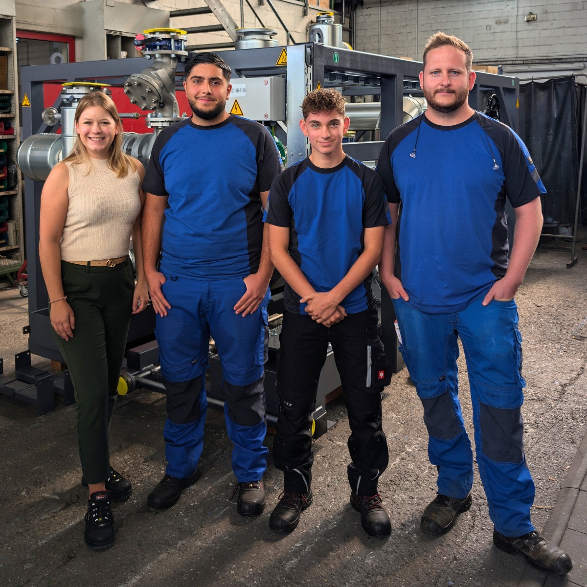 Zwei neue Azubis und ihre Betreuer vor einer Anlage stehend