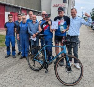 9 Personen vor dem Hauptgebäude mit einem Fahrrad